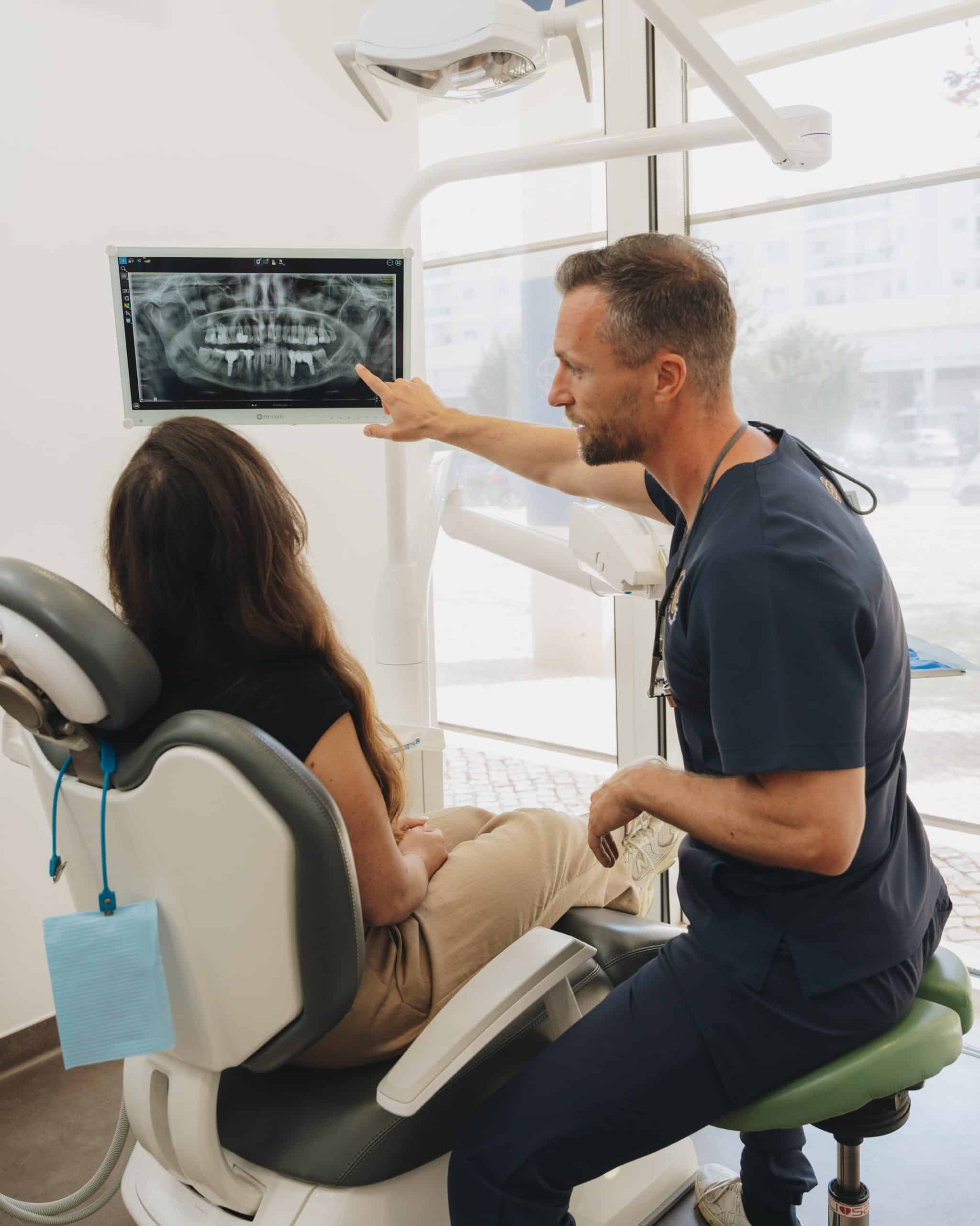 Dr. Pedro Coelho a explicar o planeamento tridimensional de um implante dentário a uma paciente na clínica em Oeiras